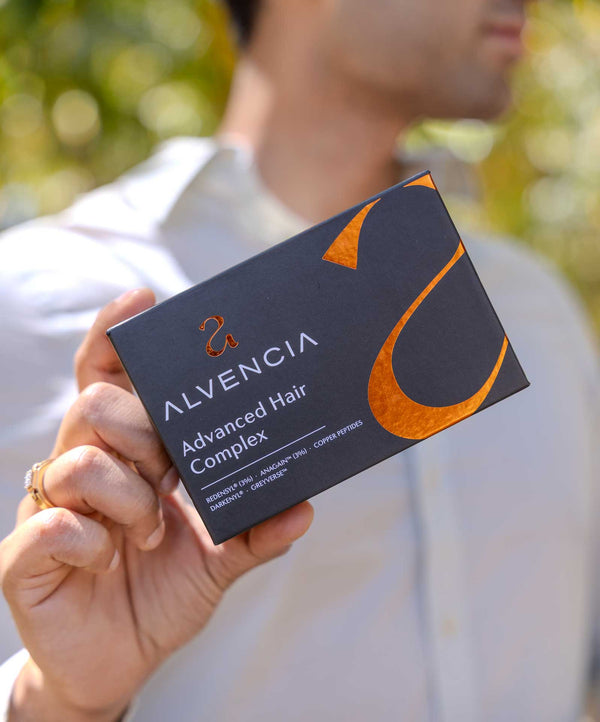 Man holding the Alvencia Advanced Hair Complex box