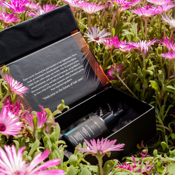 Open Alvencia box with serum bottle among pink flowers